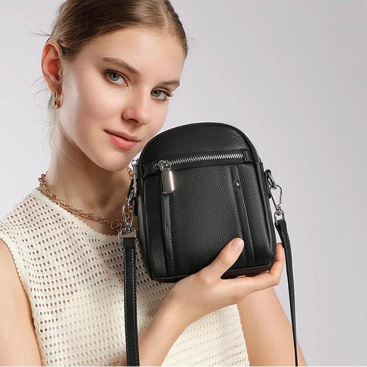 Woman wearing mini genuine leather crossbody bag in black — lifestyle shot, casual everyday style