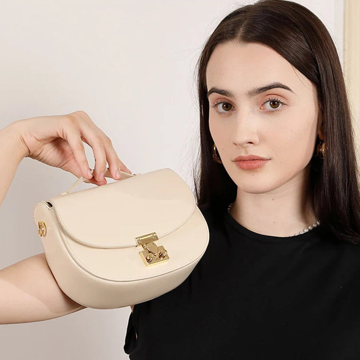 Woman presenting buckle saddle beige white bag — retro crossbody worn on the shoulder, casual chic everyday style
